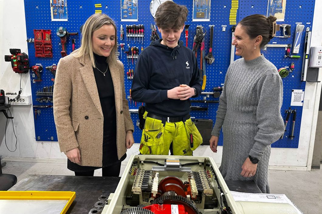 Sporveiens signalmontørlærling, Herman Osvold Askheim forklarer byråd for miljø og samferdsel Marit Vea (V) og byråd for utdanning Julie Remen Midtgarden (H) om signalsystemet og demonstrerte hvordan en drivmaskin fungerer mekanisk.